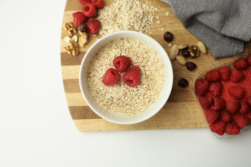 Overhead view of a bowl of oatmeal topped with berries and nuts, next to slices of whole-grain bread.